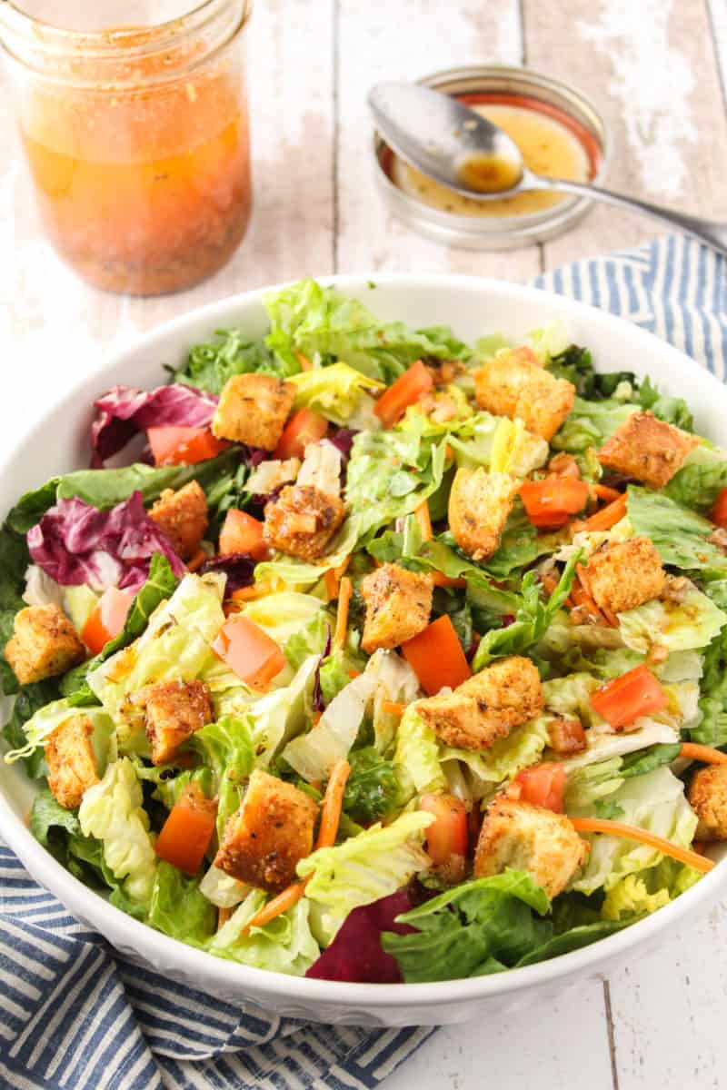 green salad topped with Italian dressing in a shallow bowl