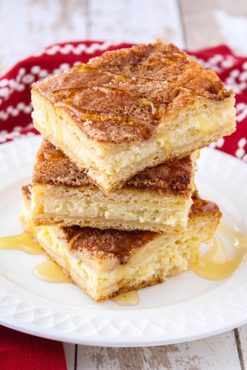 stack of 3 sopapilla cheesecake slices on a plate drizzled in honey