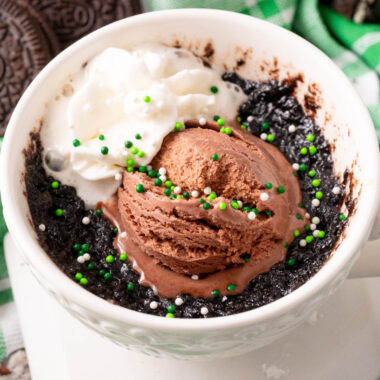 square image of irish cream oreo mug cake with chocolate ice cream, whipped, cream and green sprinkles