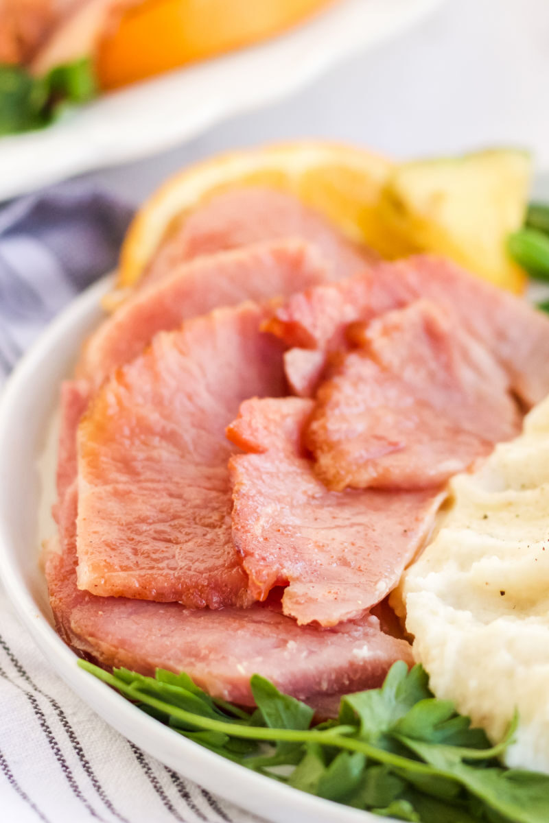slices fo instant pot ham on a plate with mashed potatoes and orange slices
