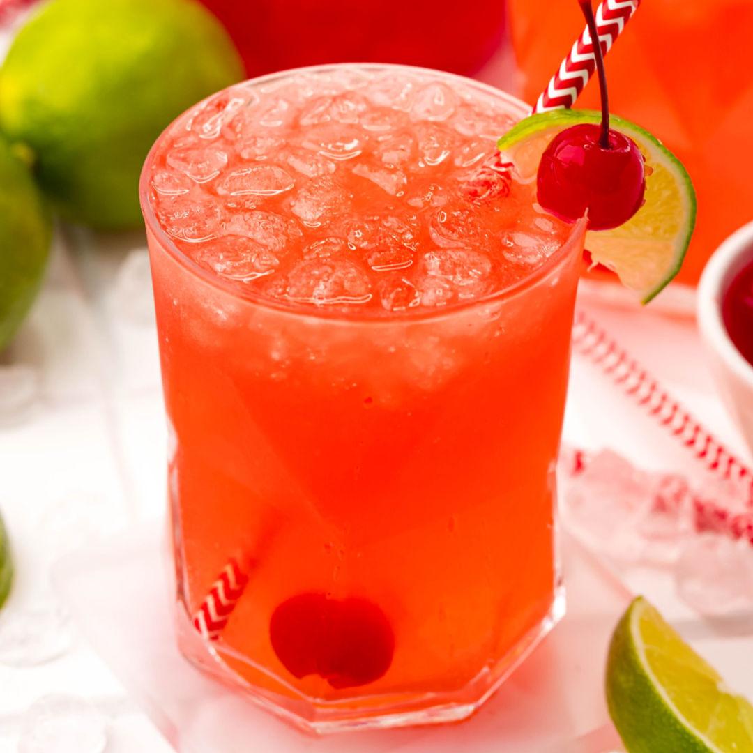 square image of copycat sonic cherry limeade in a short glass with cherry, lime slice, and a straw
