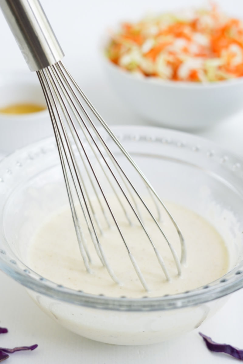 coleslaw dressing in a bowl with a whisk