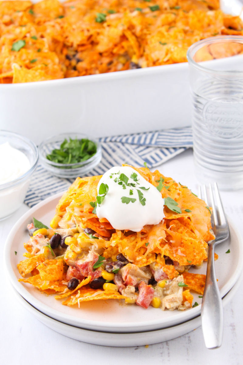 side view of dorito casserole on a plate with sour cream on top