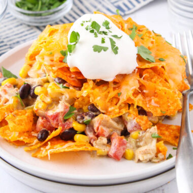 square image of dorito casserole on a plate topped with sour cream