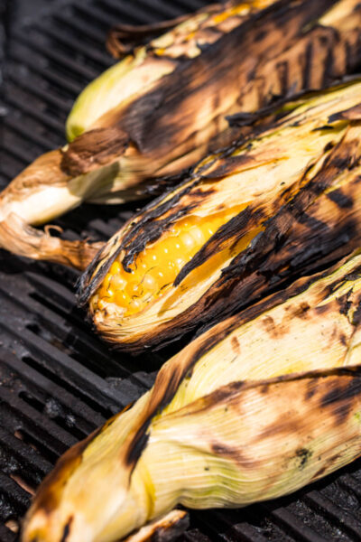 ears of corn in the husk on the grill