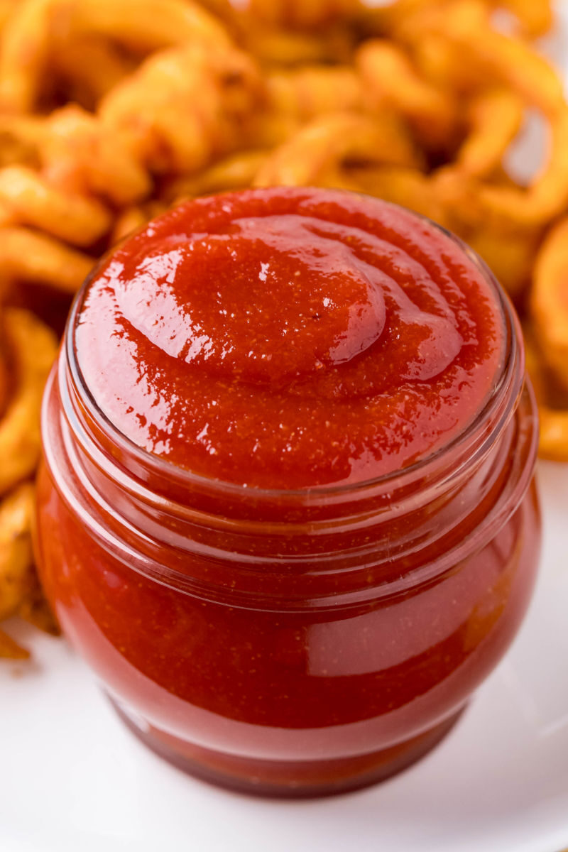 jarful of homemade ketchup with curly fries in the background