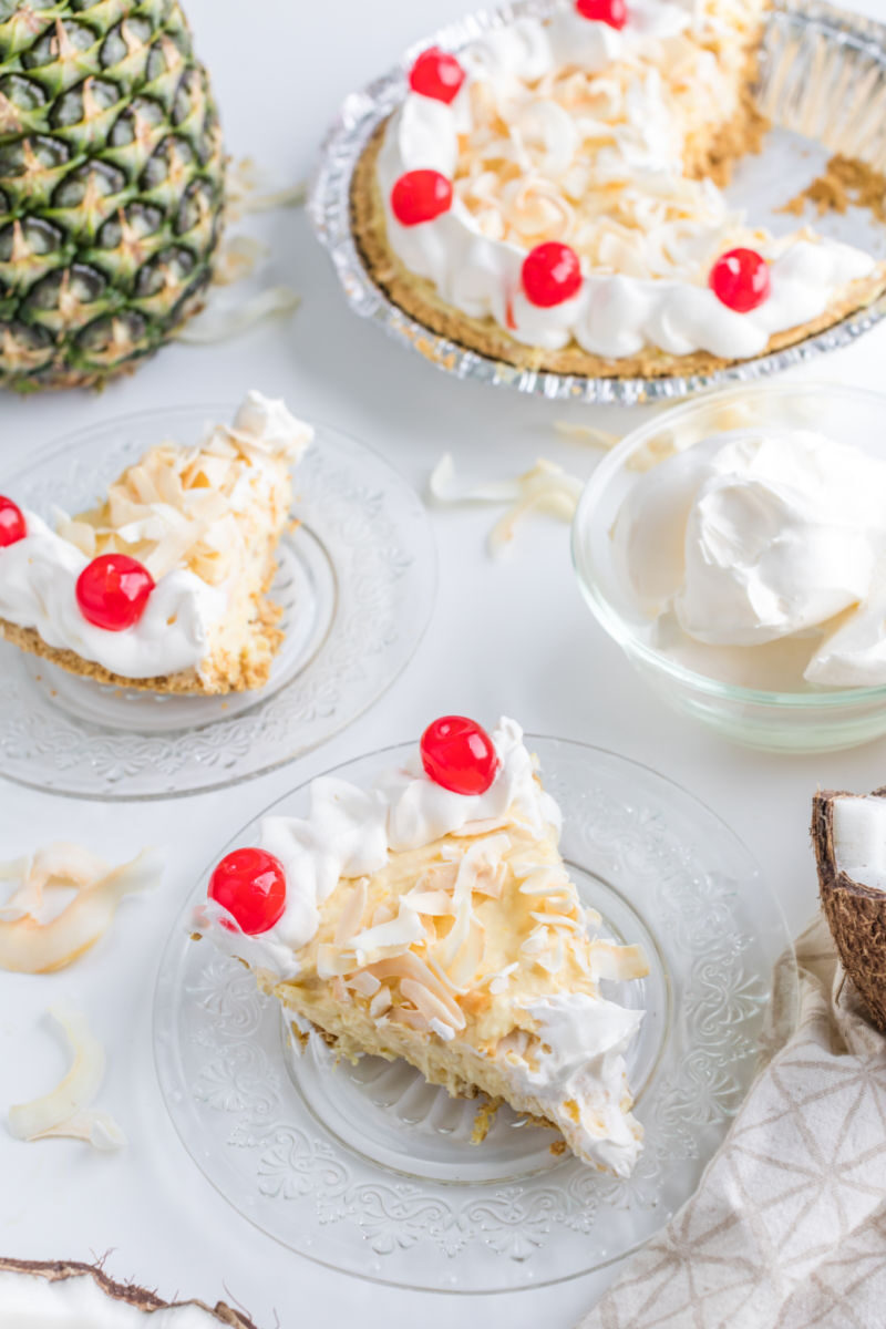 slice of pina colada pie on dessert plates next to the rest of the pie