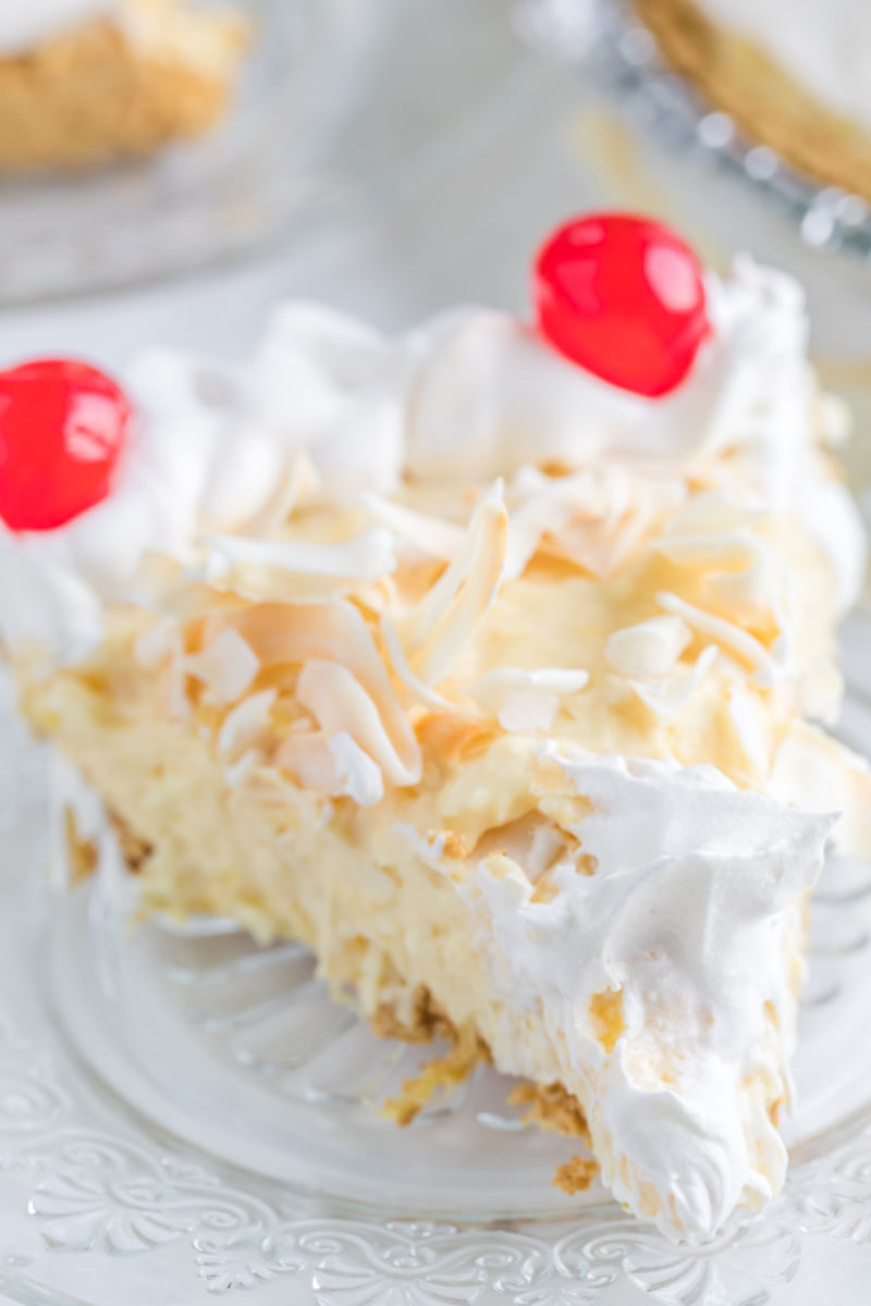 close up of pina colada pie slice garnished with whipped cream and cherries