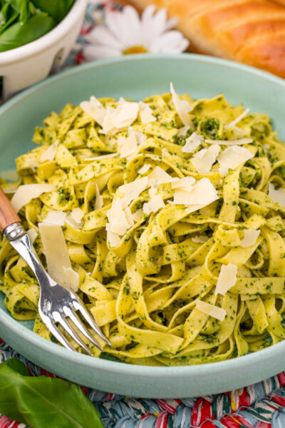 side view of a bowl of pesto pasta topped with parmesan