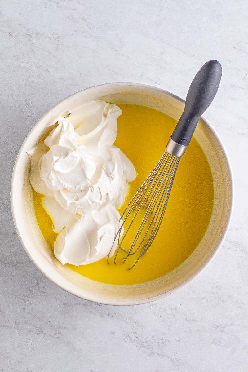 cool whip added to pudding mixture in a bowl with a whisk
