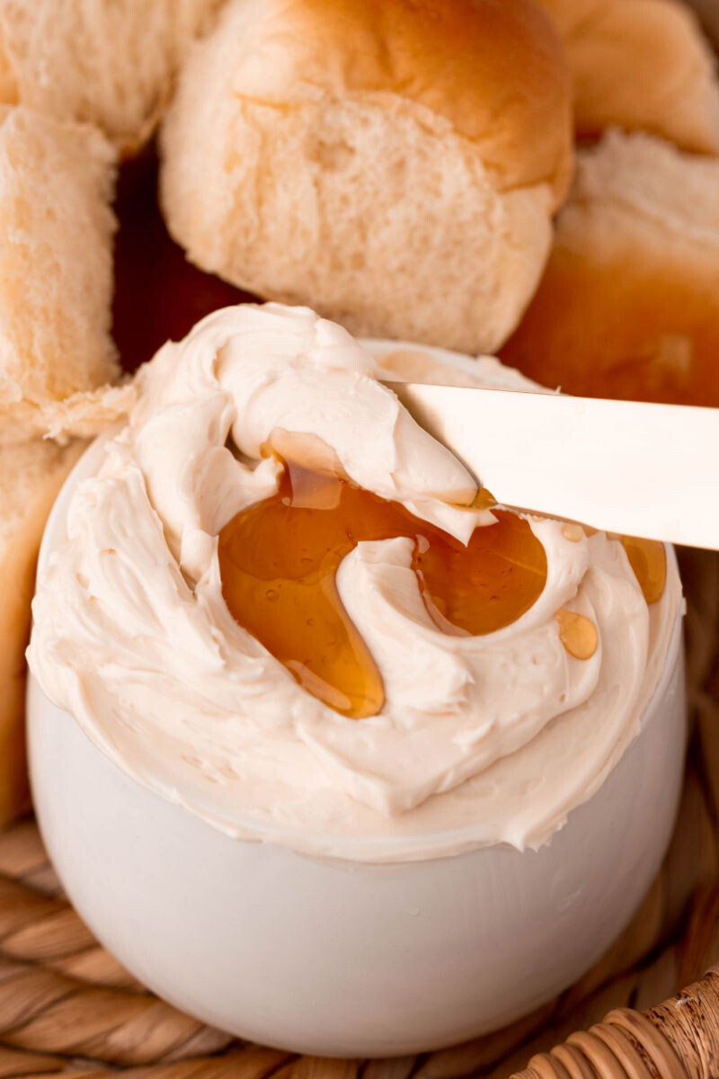 butter knife dipping into a bowl of honey butter topped with more honey