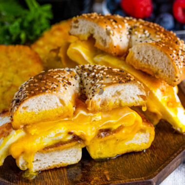 square image of a bacon, egg & cheese bagel breakfast sandwich cut in half on a plate
