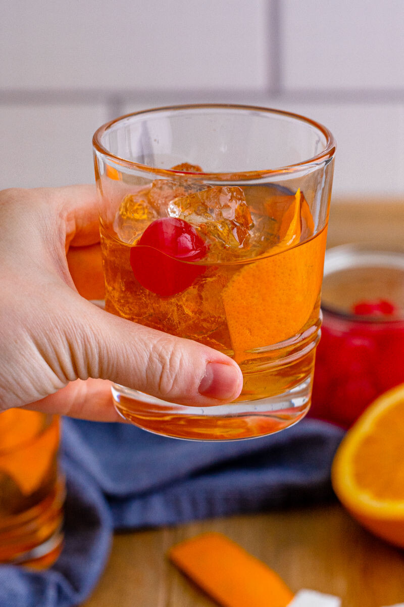 hand holding an old fashioned cocktail in a rocks glass