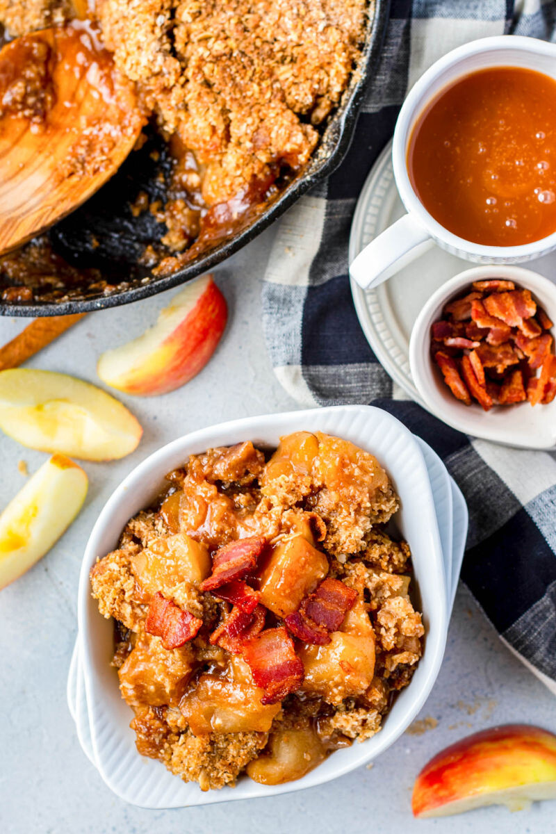 portion of bacon apple crisp in a white bowl topped with bacon