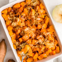 square image of maple glazed sweet potatoes with bacon in a baking dish