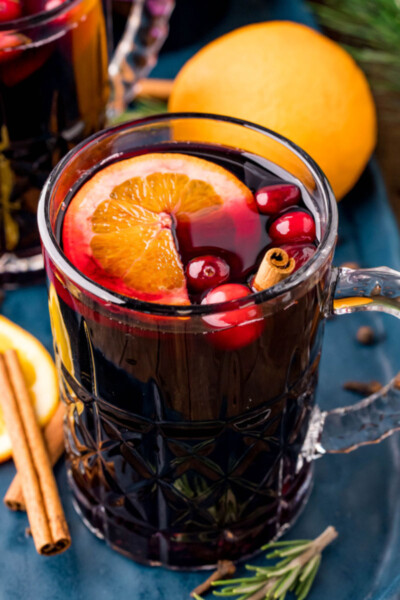 close up of a mug of mulled wine with and orange slices, cranberries, and cinnamon stick for garnish