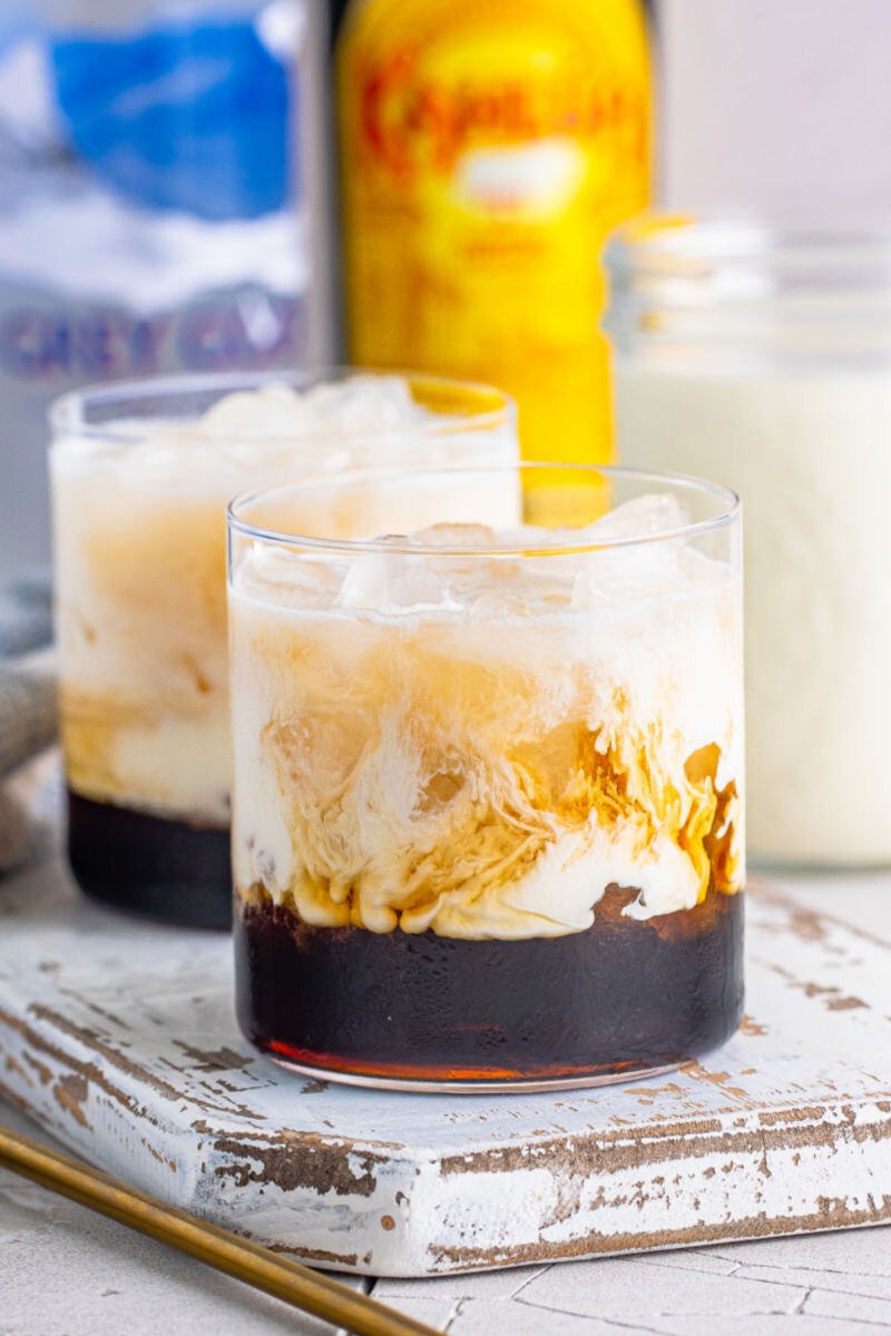 two white russian cocktail in fron of bottles of vodka and kahlua