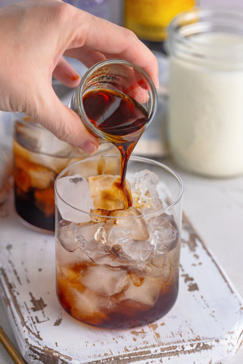 kahlua being poured into a rocks glass with vodka and ice