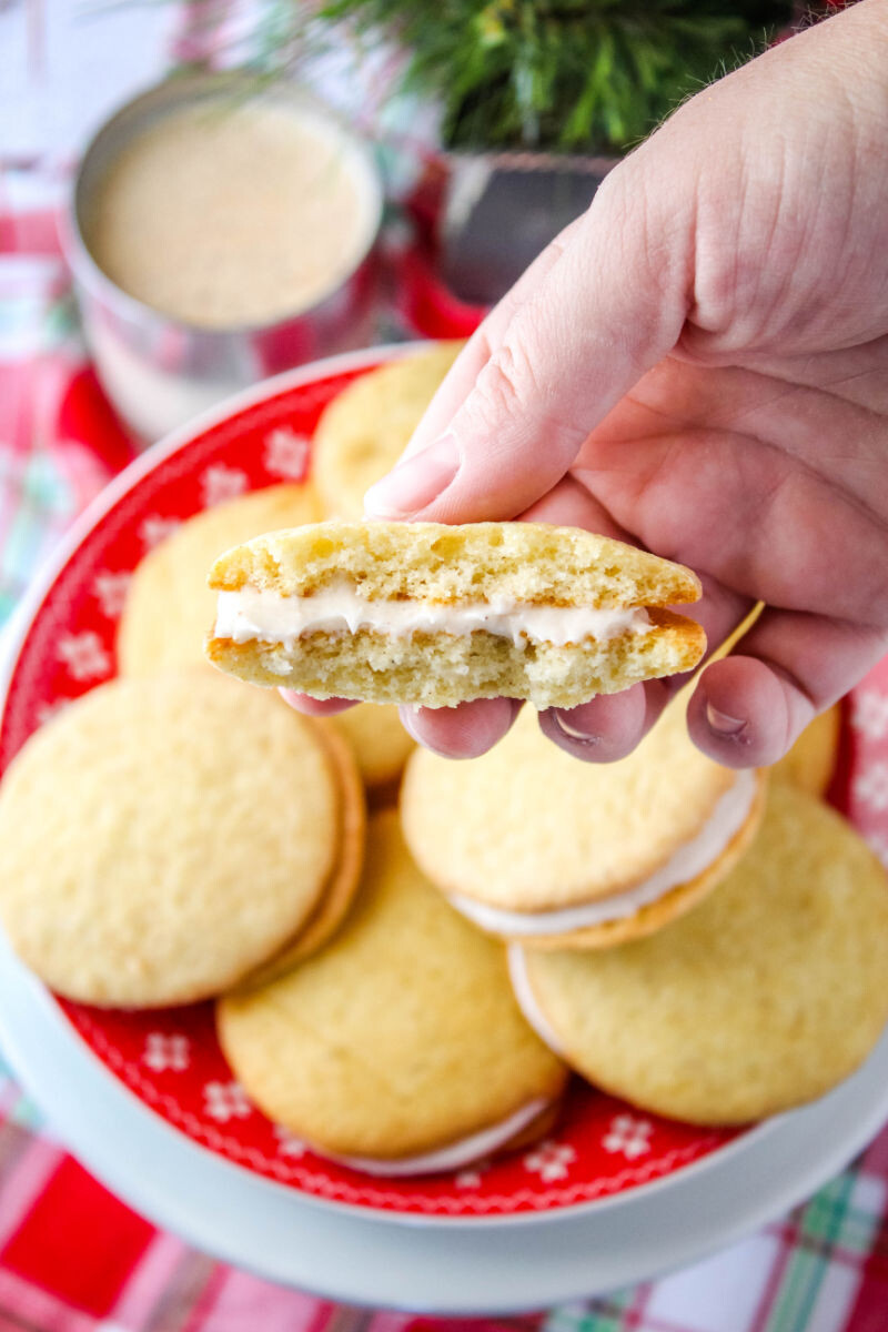 hand holding an eggnog whoopie pie broken in half to show the filling