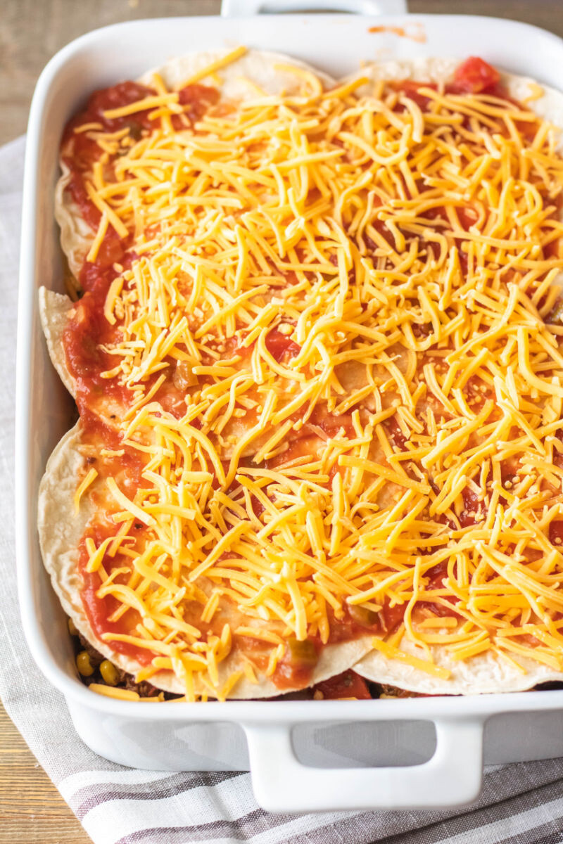 mexican lasgana topped with salsa and shredded cheddar cheese