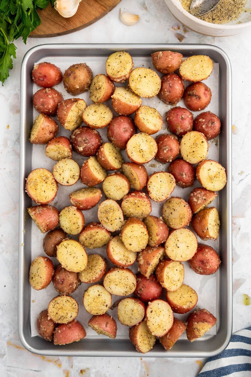 baby red potatoes toseed in cornstarch and parmesan oil mixture on a baking sheet