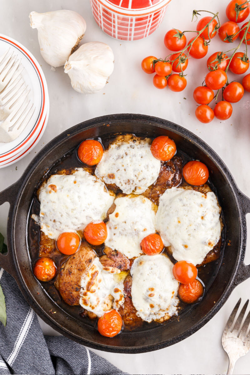 baked chicken thighs with balsamic glaze, cherry tomatoes, and mozzarella in a cast iron skillet