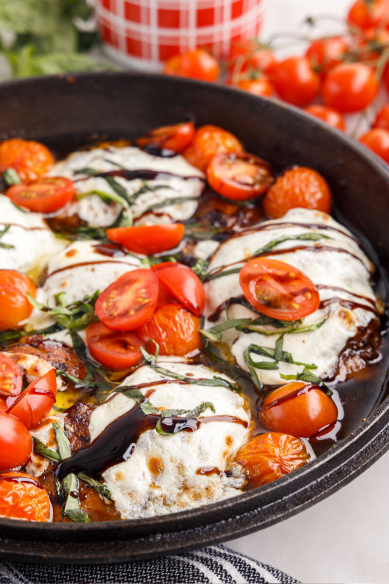side view of caprese baked chicken thighs in a cast iron skillet
