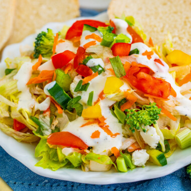 square image of chopped salad on a small plate topped with ranch dressing