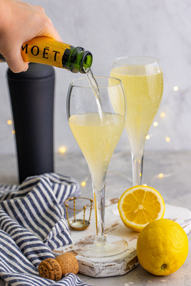 champagne being poured into a flute with sweetened lemon juice and gin