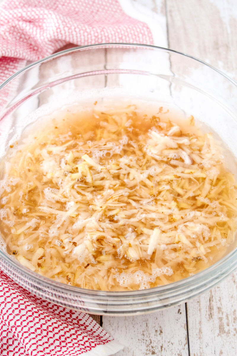 shredded potatoes soaking in a bowl of cold water