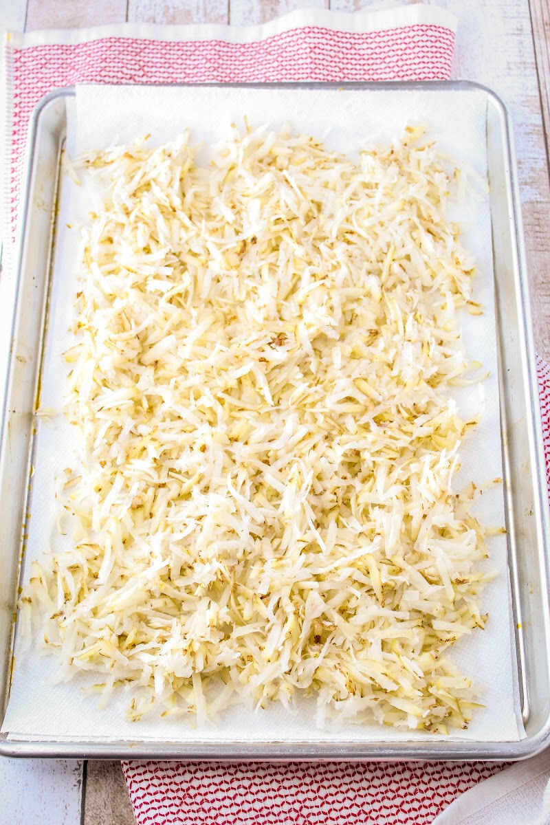 rinsed shredded potatoes on a paper towel-lined baking sheet