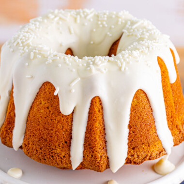 square image of Air Fryer Pumpkin Bundt Cake is fluffy and moist with a subtle pumpkin spice flavor. Topped with cream cheese glaze, this cake irresistible! #AppetizersAndDesserts #airfryer #pumpkin #bundtcake #pumpkincake #creamcheese #glaze #thanksgiving #fall #dessert with cram cheese glaze and white sprinkles