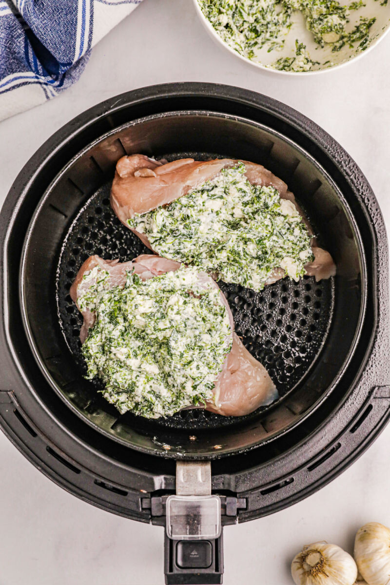 stuffed chicken breasts in an air fryer basket before cooking