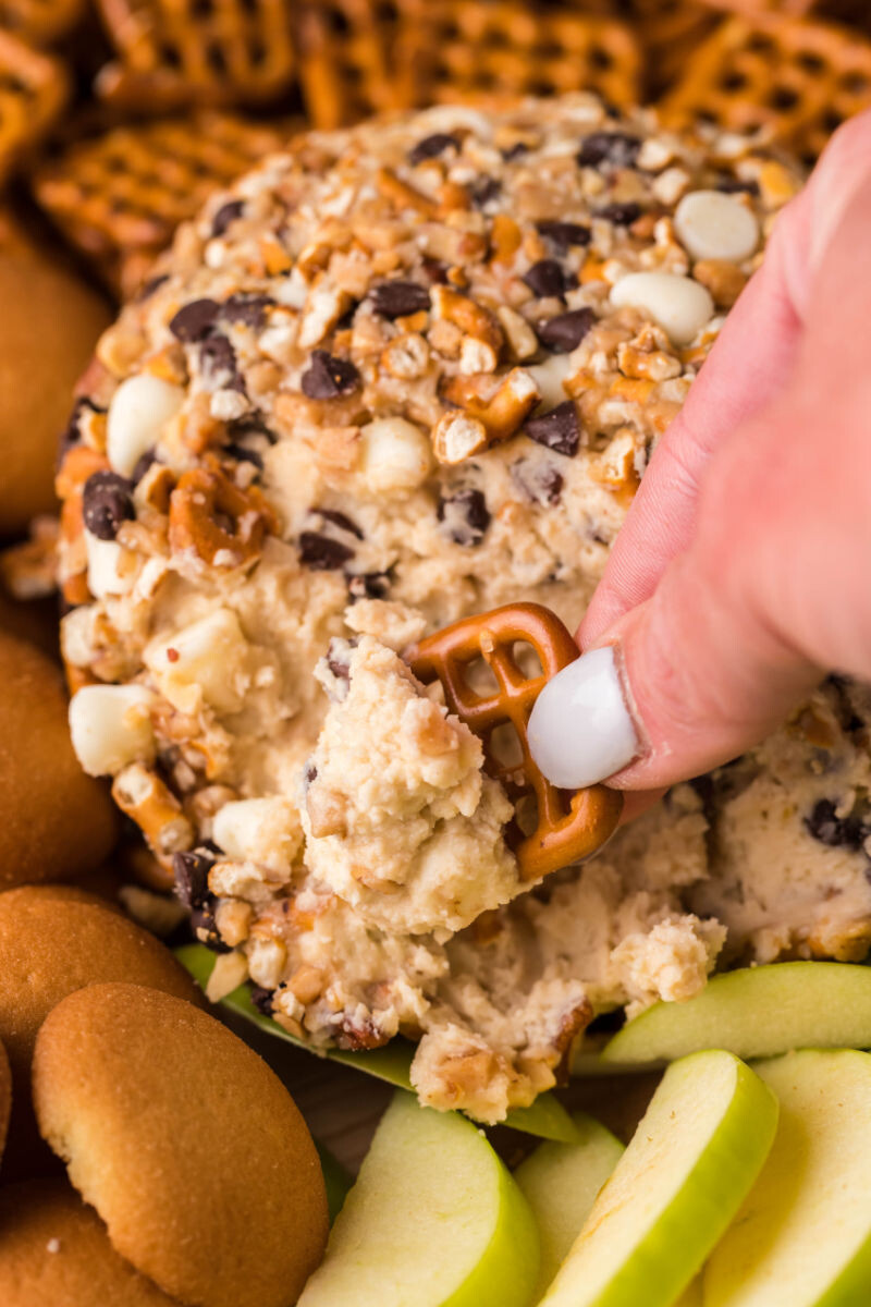 pretzel being dipped into a chocolate chip cheese ball
