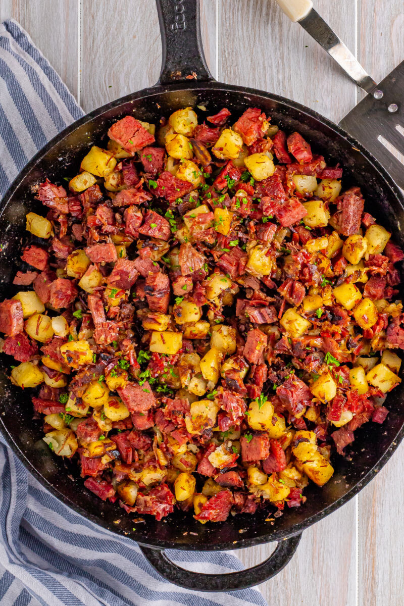 corned beef hash in a skillet with chopped parsley sprinkled on top