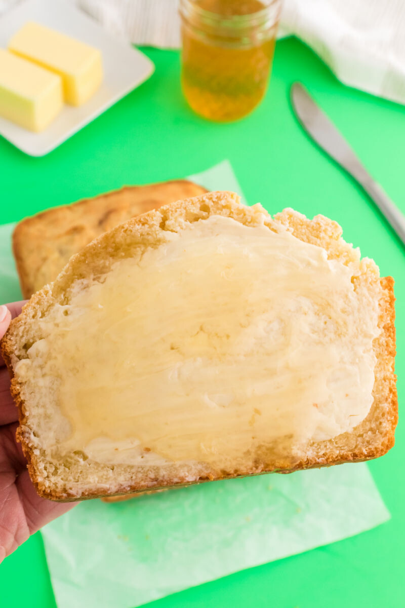 hand holding a slice of irish soda bread with butter and honey on it