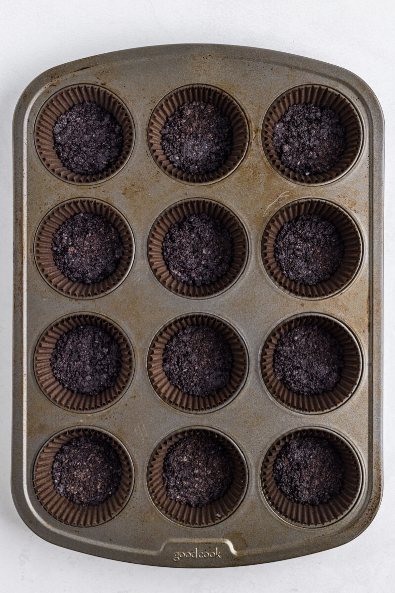 looking down at oreo cookie crust in lined muffin tin cups