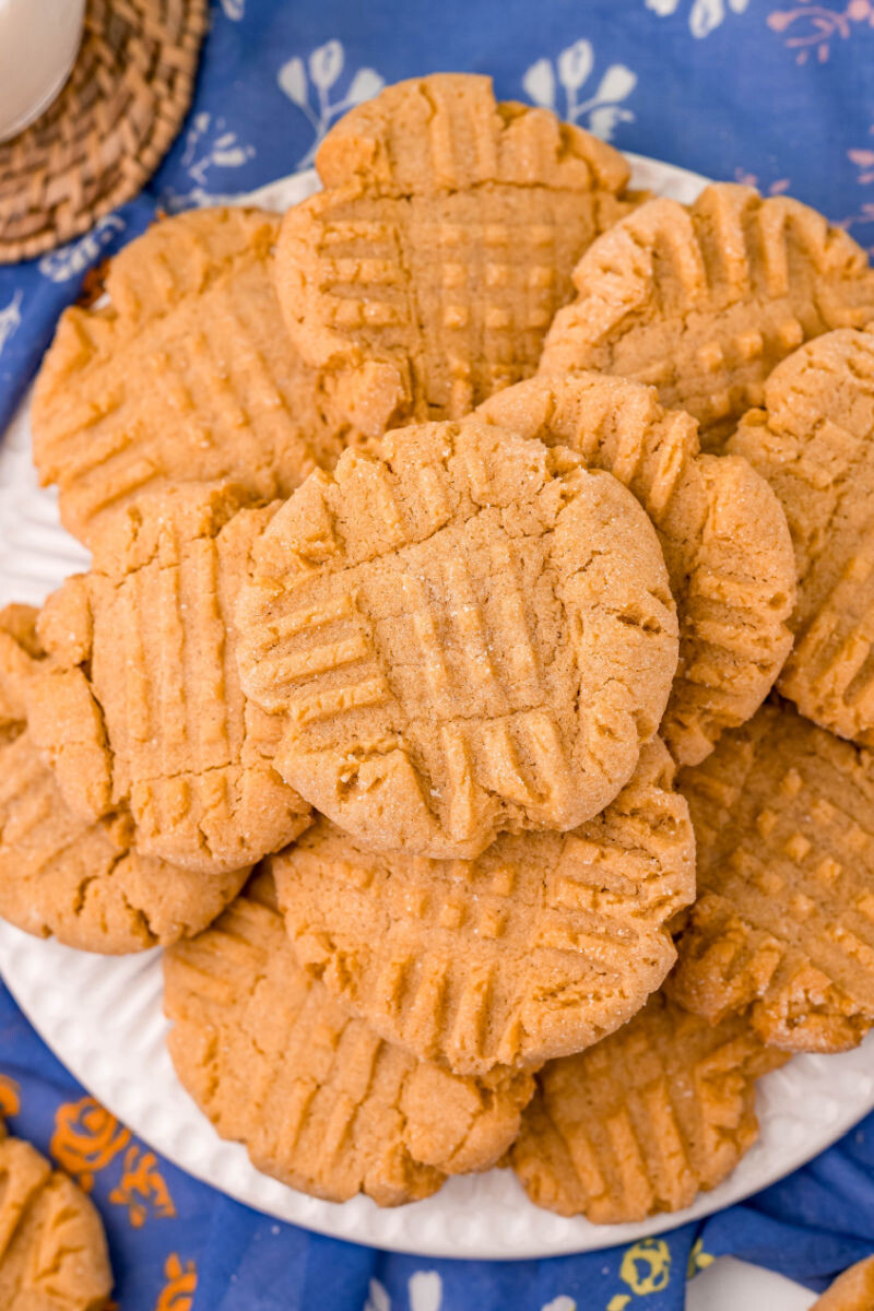 looking down at a white plate with a pile on peanut butter cookies
