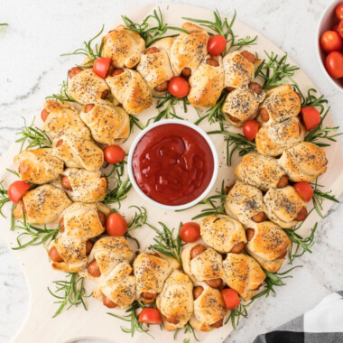 square image of a pigs in a blanket wreath with a bowl of ketchup in the center