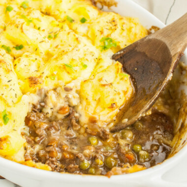 square image of shepherd's pie in a baking dish with a portion taken out to show the filling