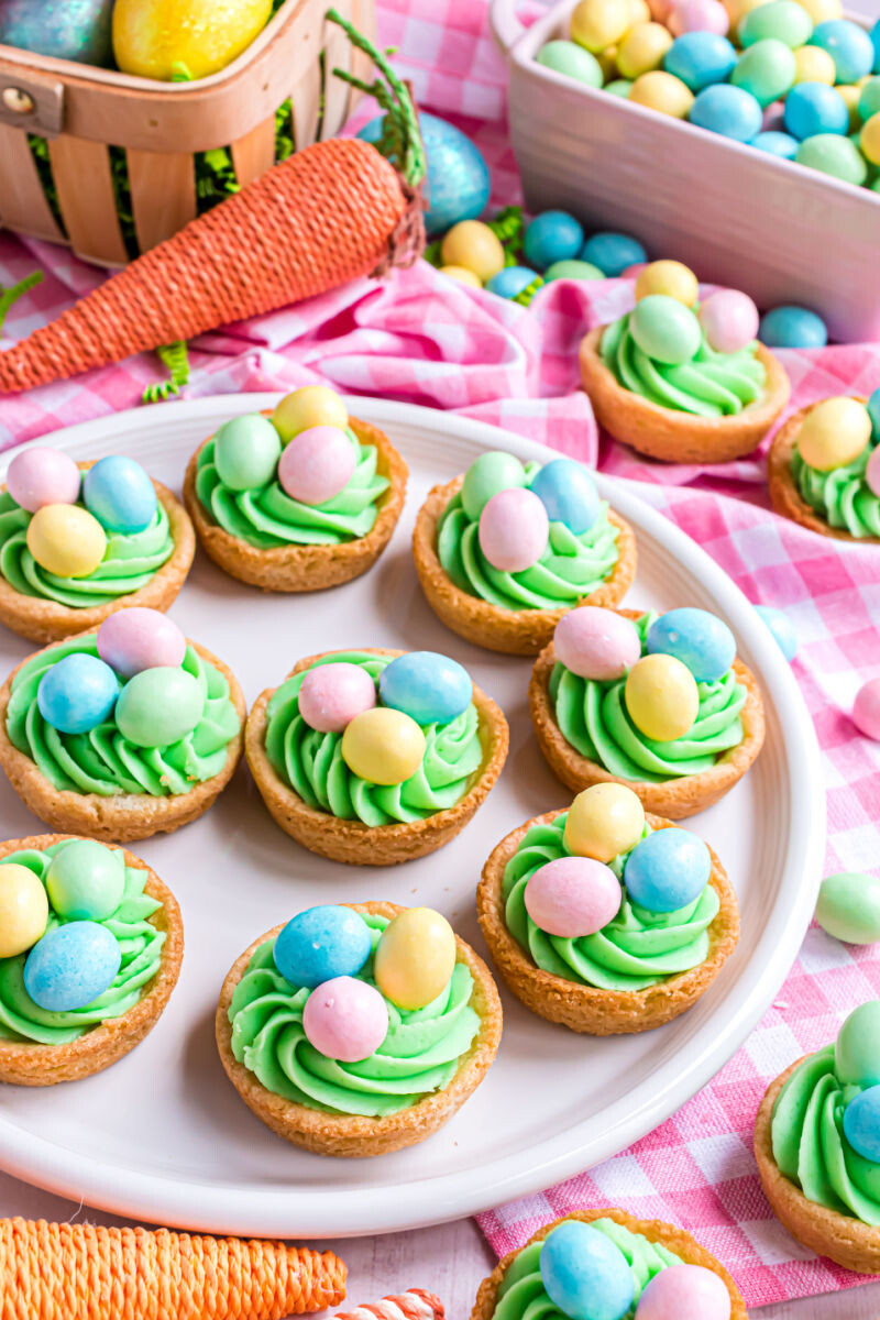 easter egg sugar cookie cups on a plate next to a basket of easter eggs