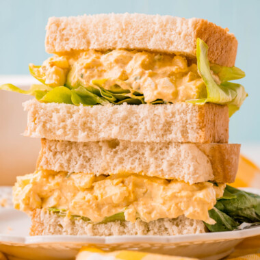 square image of an egg salad sandwich cut in half and then stacked on a plate