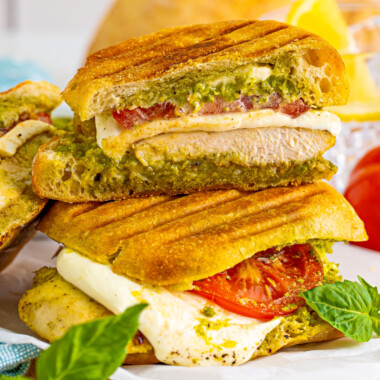 square image of half a pesto chicken sandwich sitting on top of another sandwich