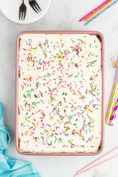 looking down at vanilla sheet cake in the pan with vanilla frosting and sprinkles