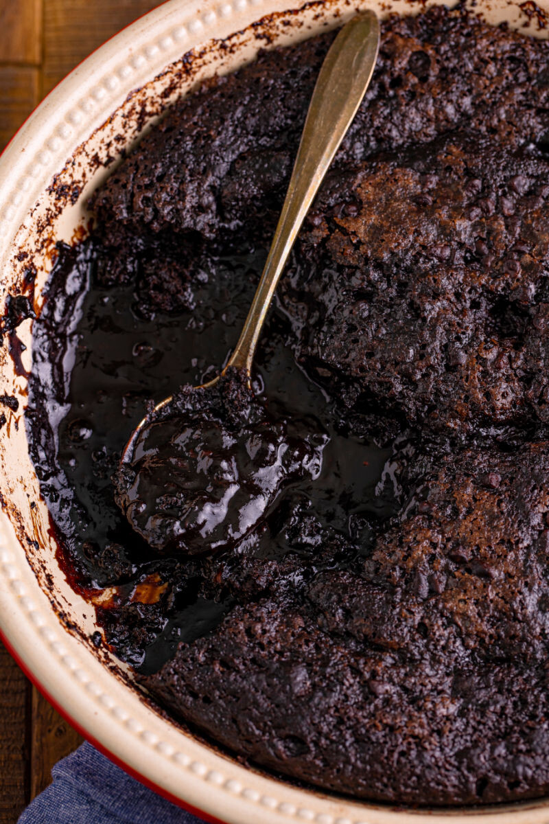 spoon in a dish of chocolate pudding cake with a portion removed to show the sauce under the cake