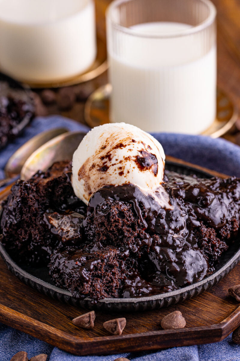 chocolate pudding cake topped with vanilla ice cream next to a glass of milk