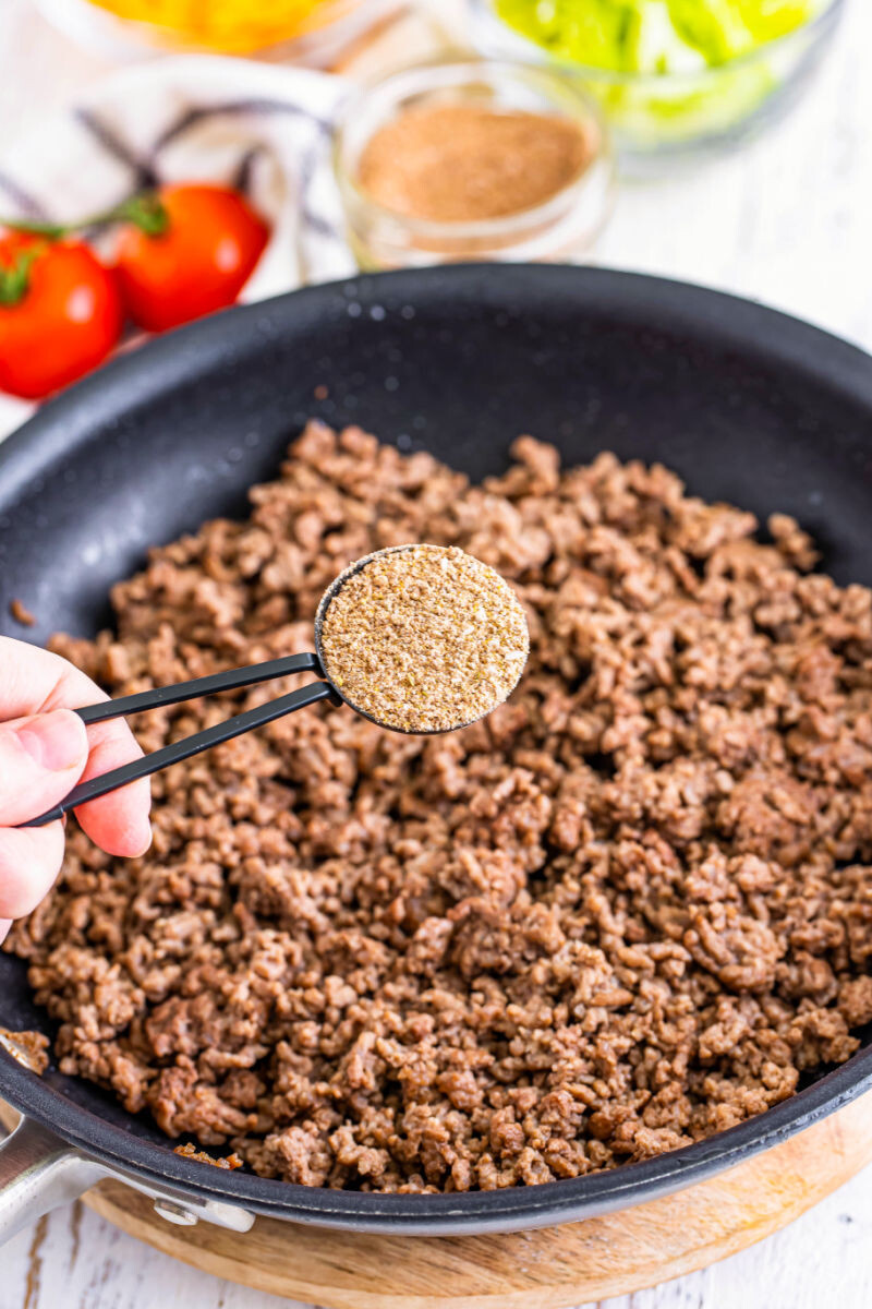tablespoon of taco seasoning over a skillet of ground beef
