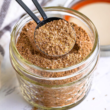 square image of a tablespoons of taco seasoning over the jar
