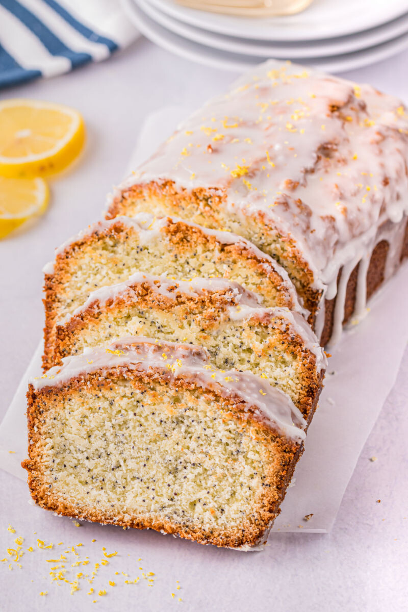 slices of almond pound cake with lemon glaze laying back against the rest of the loaf