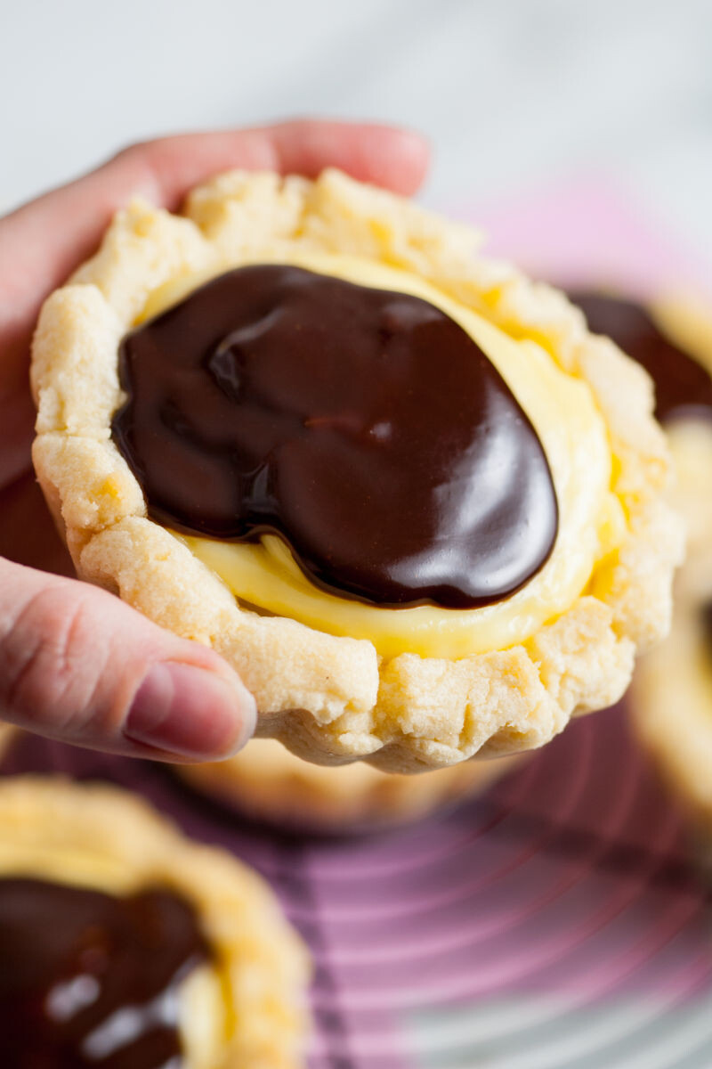 hand holding a copycat crumbl boston cream pie cookies to show how big they are